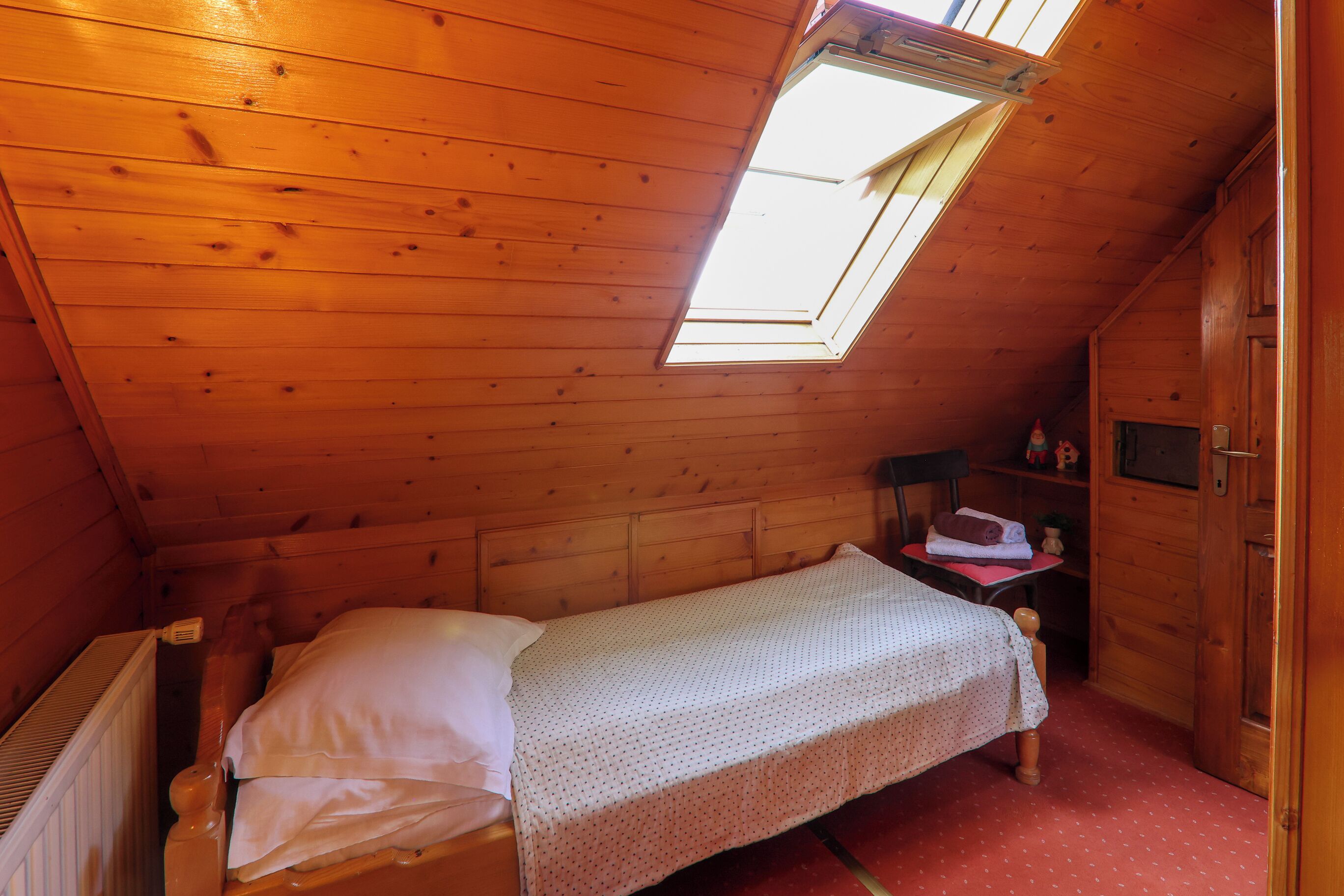 Une petite chambre avec un lit simple, un plafond en pente et un puits de lumière.