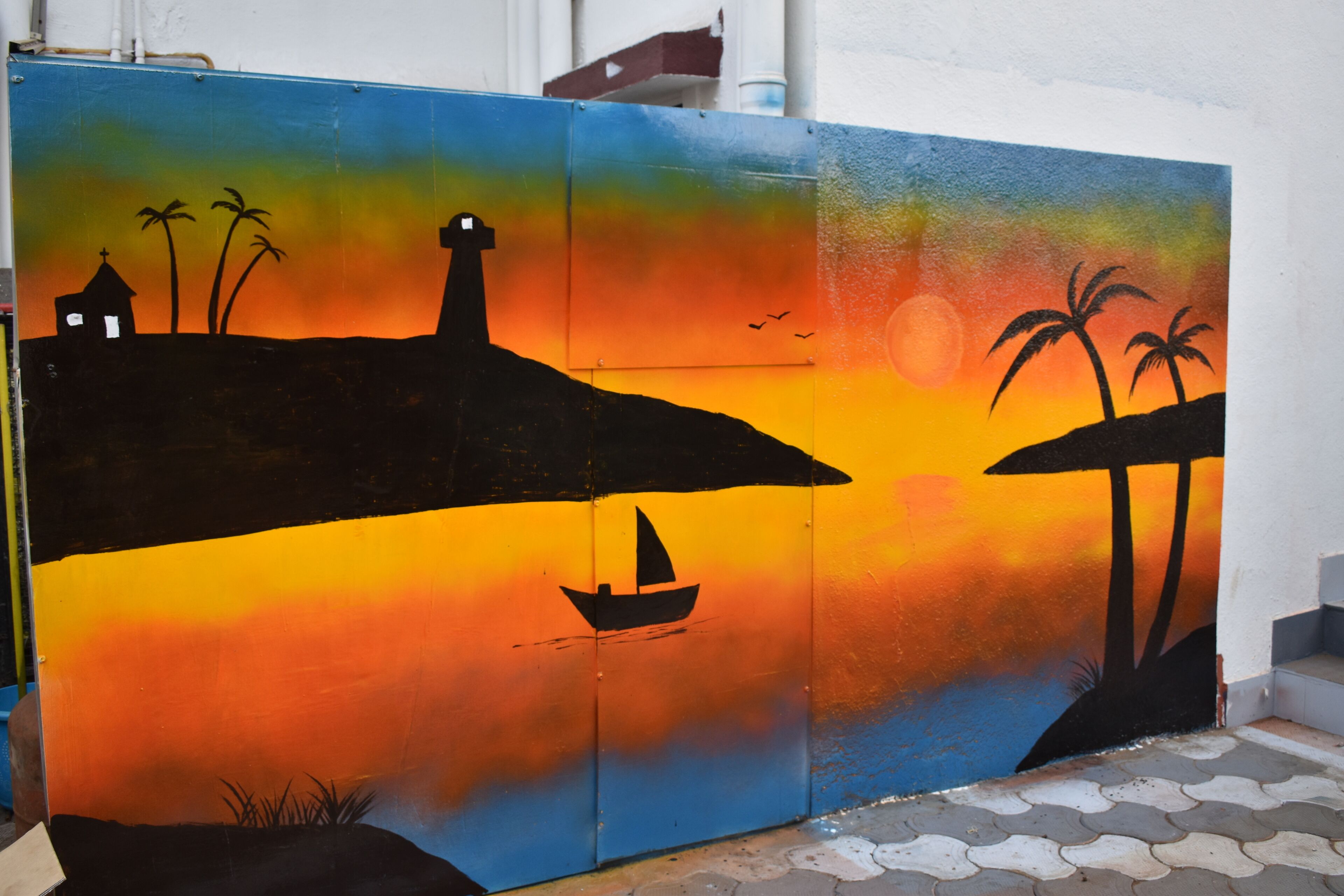 A colorful mural with a sunset, palm trees, a lighthouse, and a sailboat.