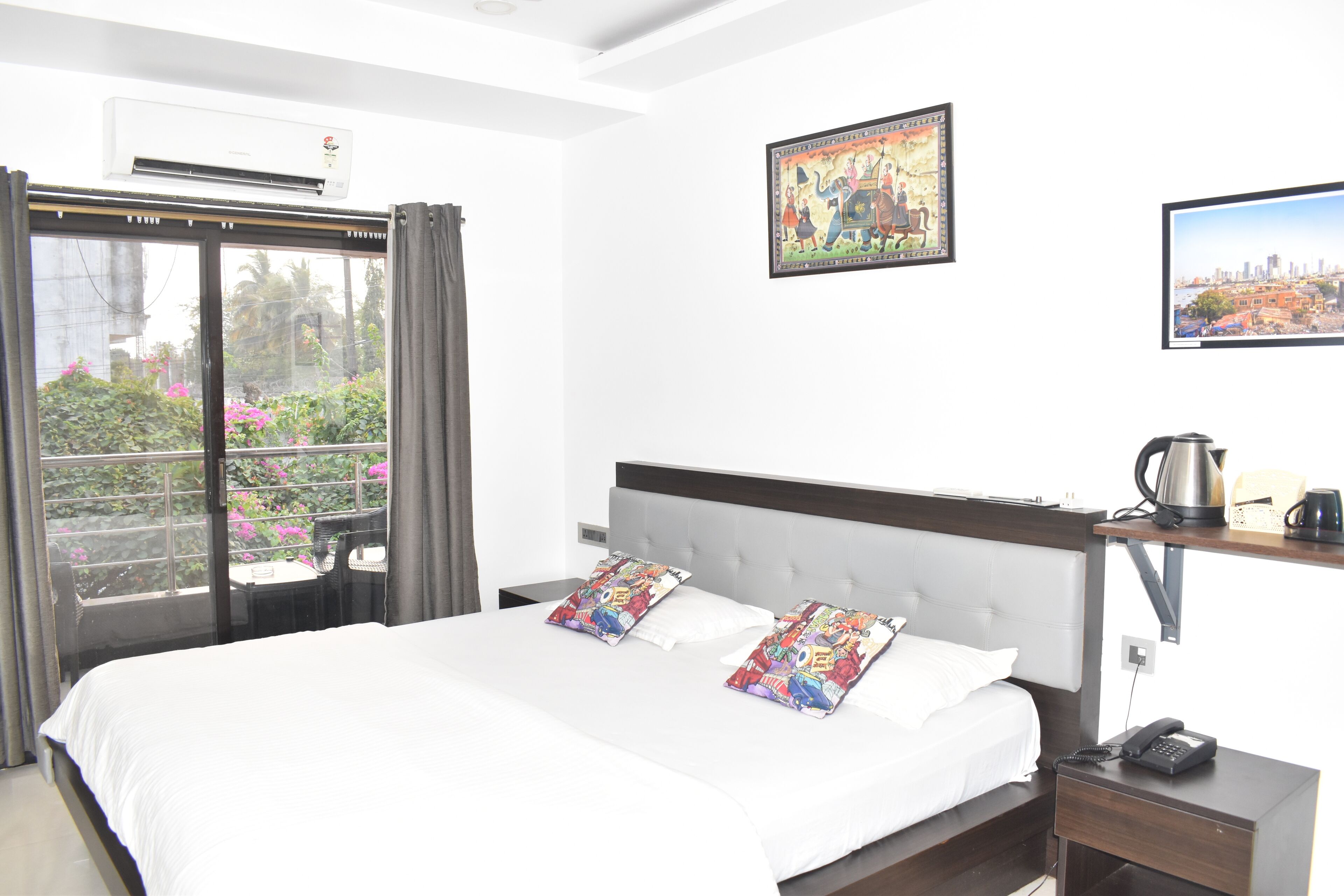 A hotel room with a large bed, a desk with a phone, a coffee maker, and a TV on the wall.