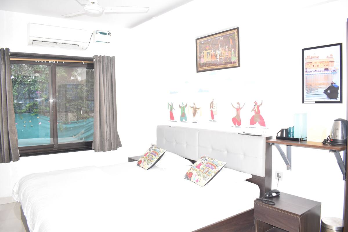 Ein Hotelzimmer mit Bett, Schreibtisch, Stuhl, Fenster und Deckenventilator.