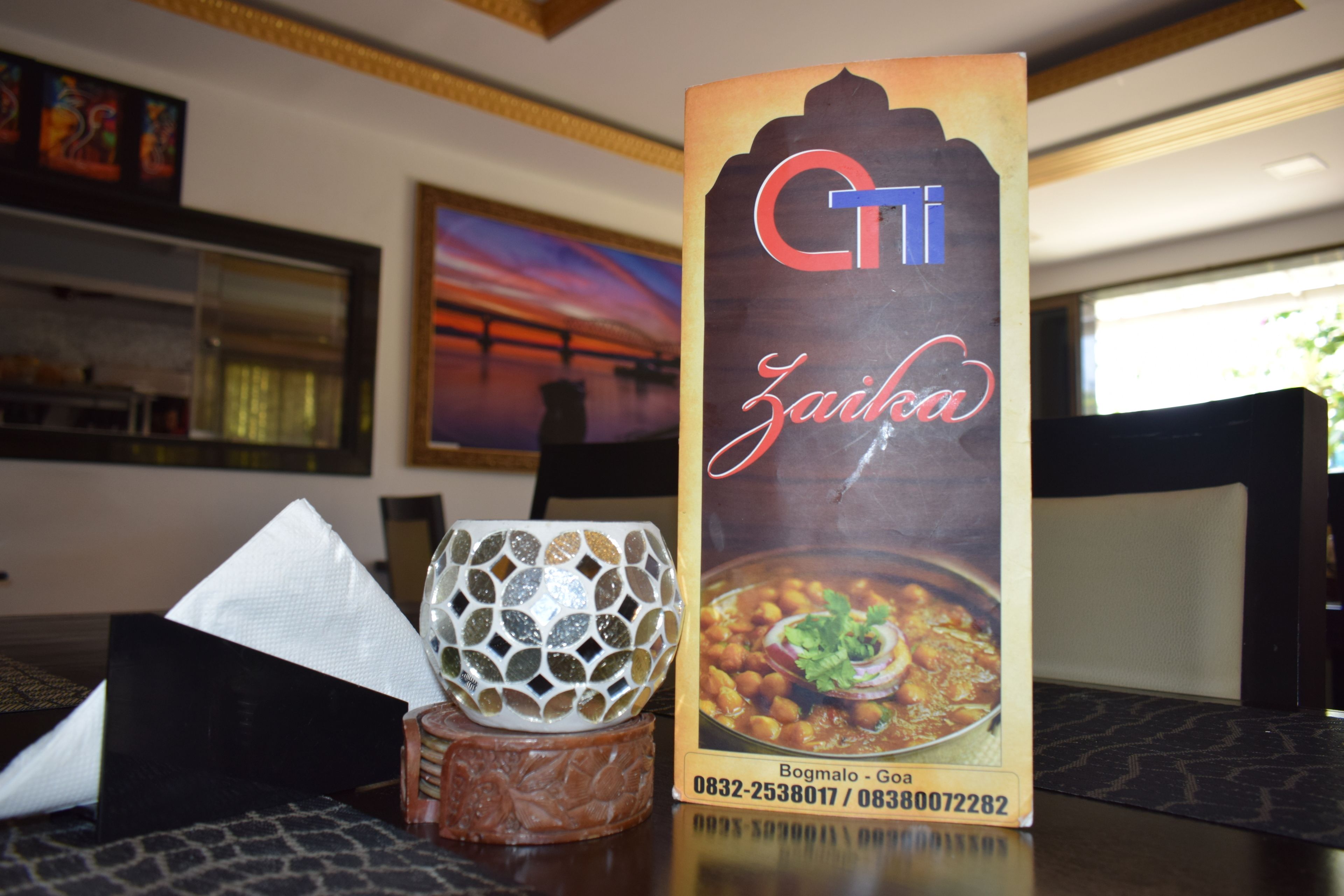 Uma mesa com um menu, um copo decorativo e uma guardanapo.