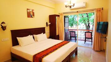 Quarto de hotel com cama grande, ventilador de teto, lustre e vista para o exterior.
