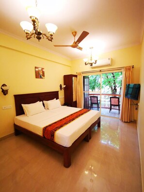 Habitación de hotel con una cama grande, ventilador de techo, candelabro y vistas al exterior.