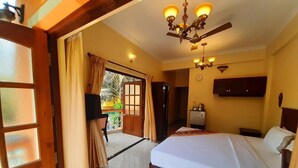 Une chambre d’hôtel équipée d’un lit, d’un ventilateur de plafond, d’une télévision et offrant une vue sur l’extérieur.