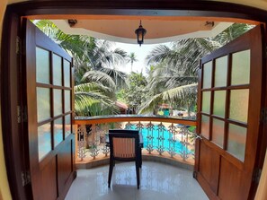 Un balcón con vistas a una piscina, rodeado de palmeras.