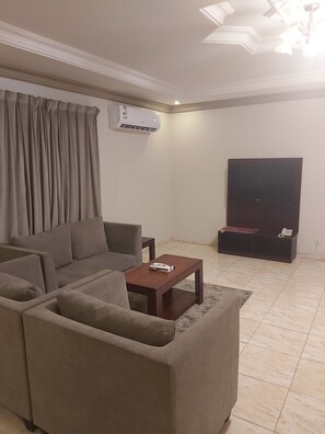 Un salon comprenant un canapé, une table basse, un téléviseur à écran plat et un appareil de climatisation.