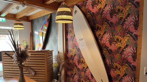 Un comptoir d’accueil agrémenté d’une planche de surf, de lambris en bois et de lampes suspendues.