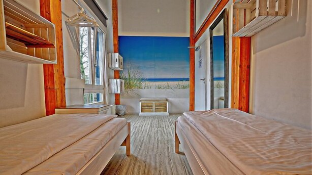Une chambre avec deux lits, une grande fenêtre et vue sur la plage.