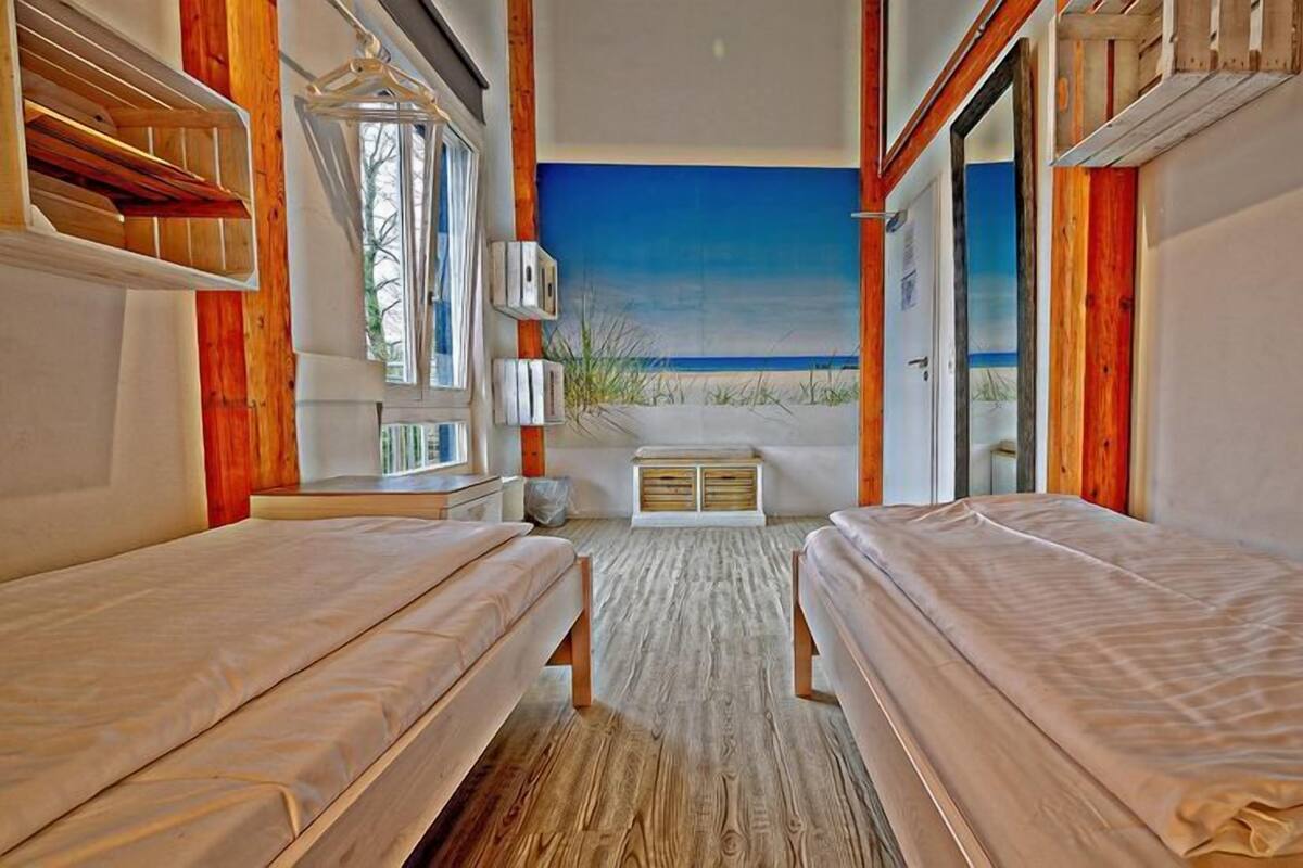 A room with two beds, a large window, and a view of the beach.