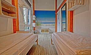 Une chambre avec deux lits, une grande fenêtre et vue sur la plage.