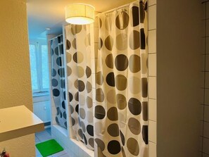 A bathroom with a shower curtain featuring a polka dot pattern, a white sink, and a green mat. - mybrand Hostel Hamburg Volksdorf (Hamburg)