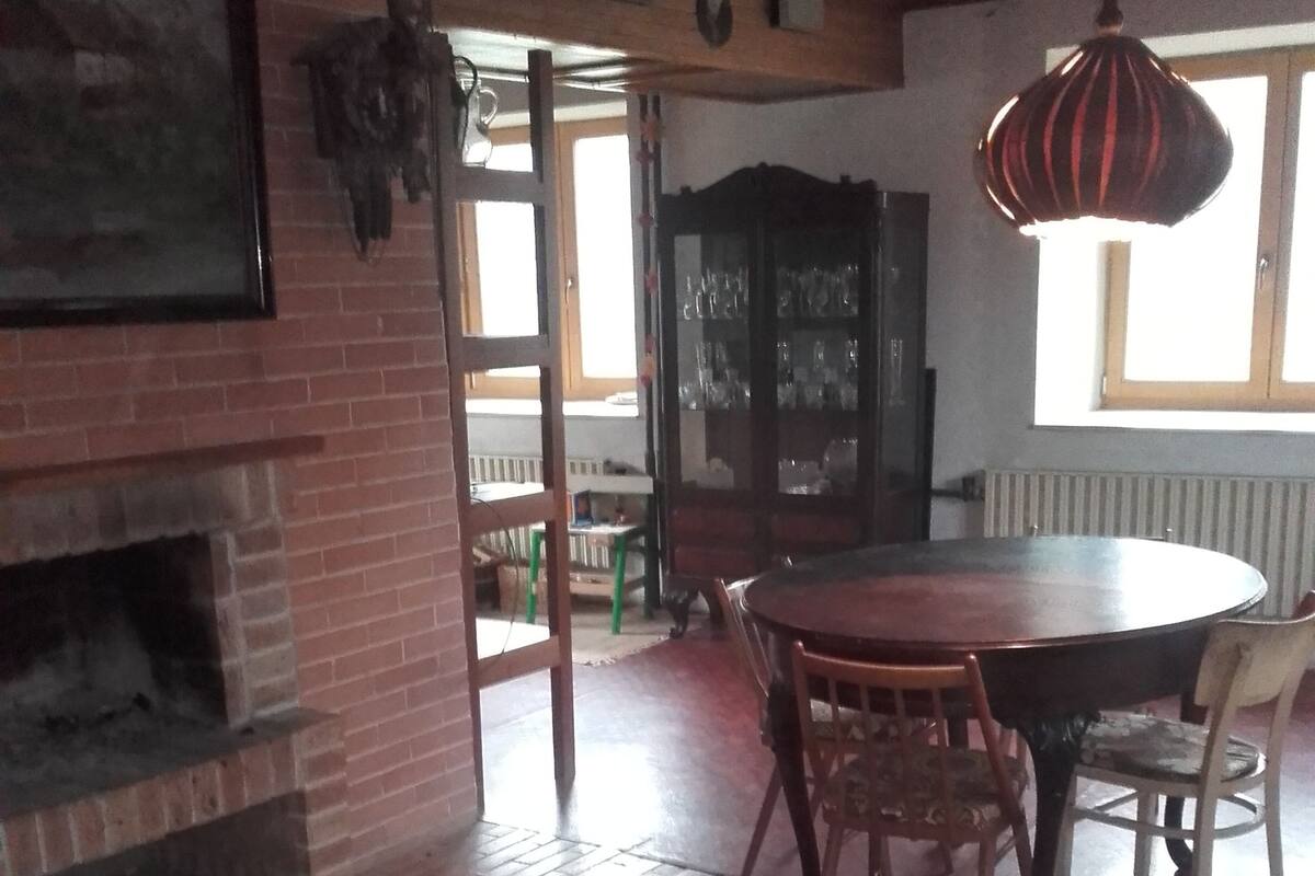 A dining area with a brick fireplace, wooden dining table, and chairs.