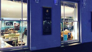 Eine Bar namens "2 Bars" mit einem Schild, auf dem "Live Here" und "Loyalty Sports" zu sehen sind, ist durch das Fenster sichtbar.