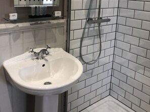 A bathroom with a white sink, a mirror, and a shower area with a glass-enclosed shower.