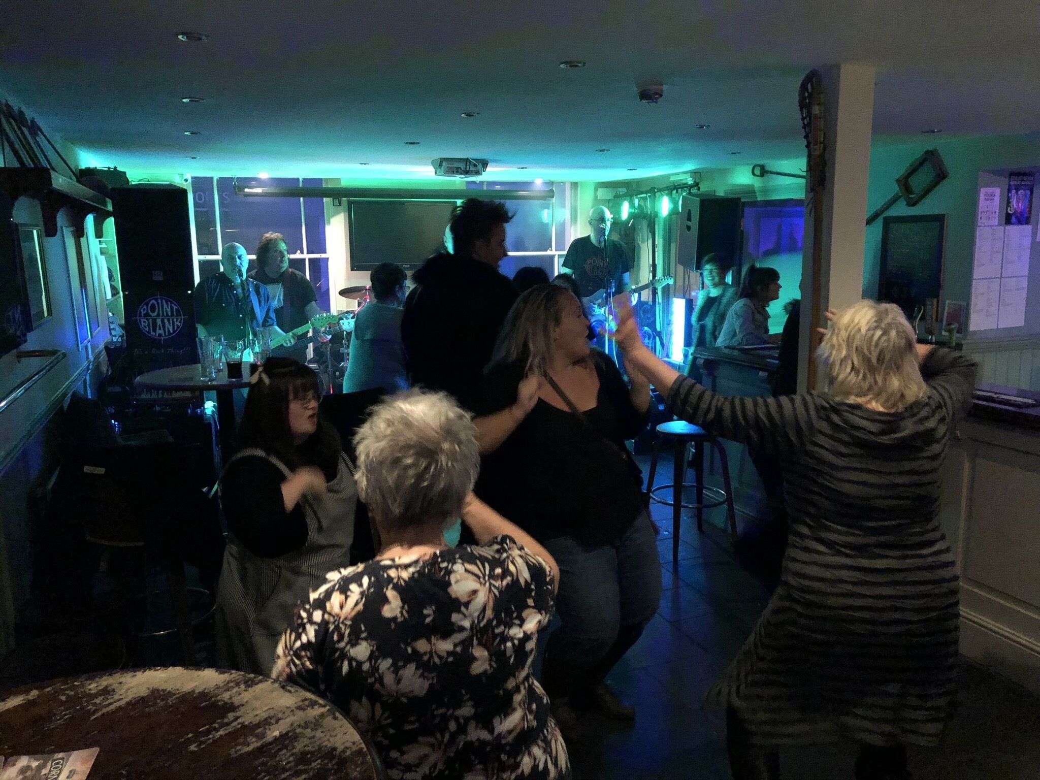 Een bar met een podium voor live muziek, krukken en een toonbank.