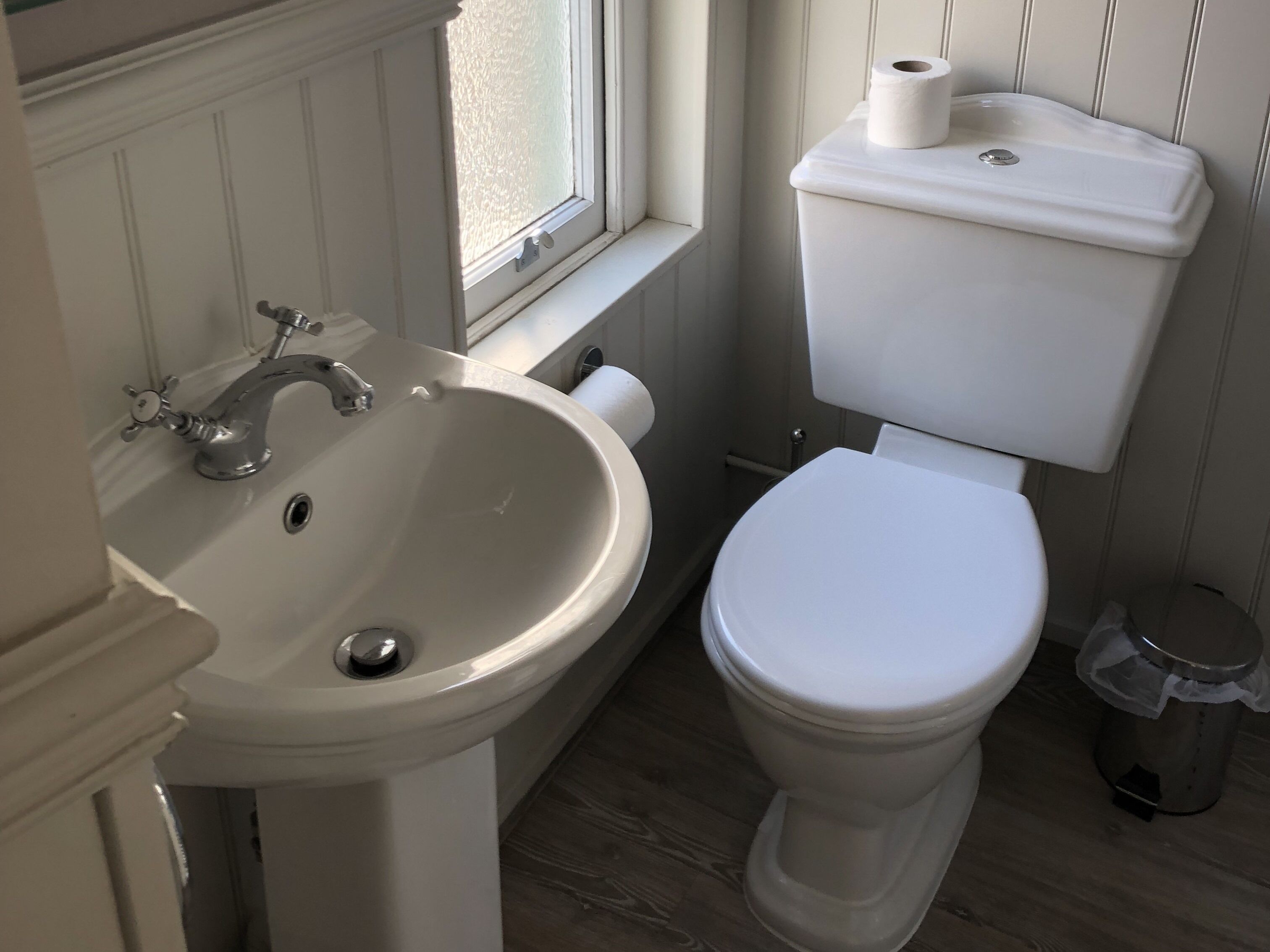A bathroom with a white sink, toilet, and window.