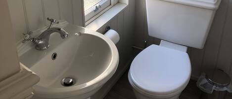 A bathroom with a white sink, toilet, and window.