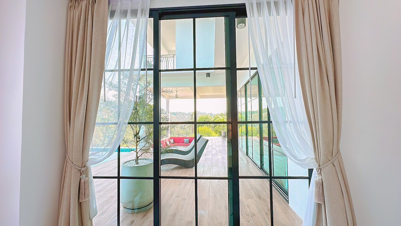 A balcony with a view of a red sofa and a potted plant.