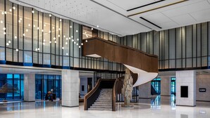 A spacious lobby with a prominent spiral staircase, large windows, and modern lighting fixtures.