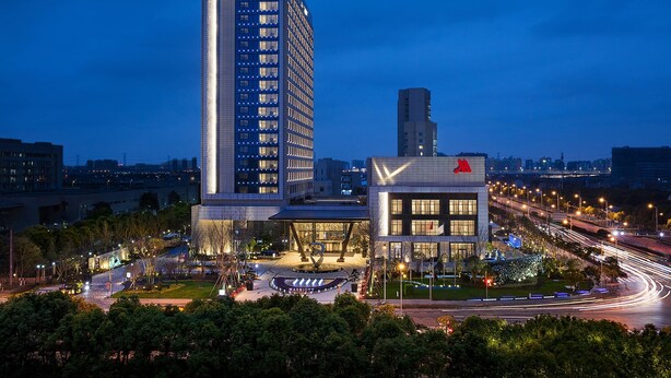A modern hotel with a tall building and a shorter structure with a checkmark logo.