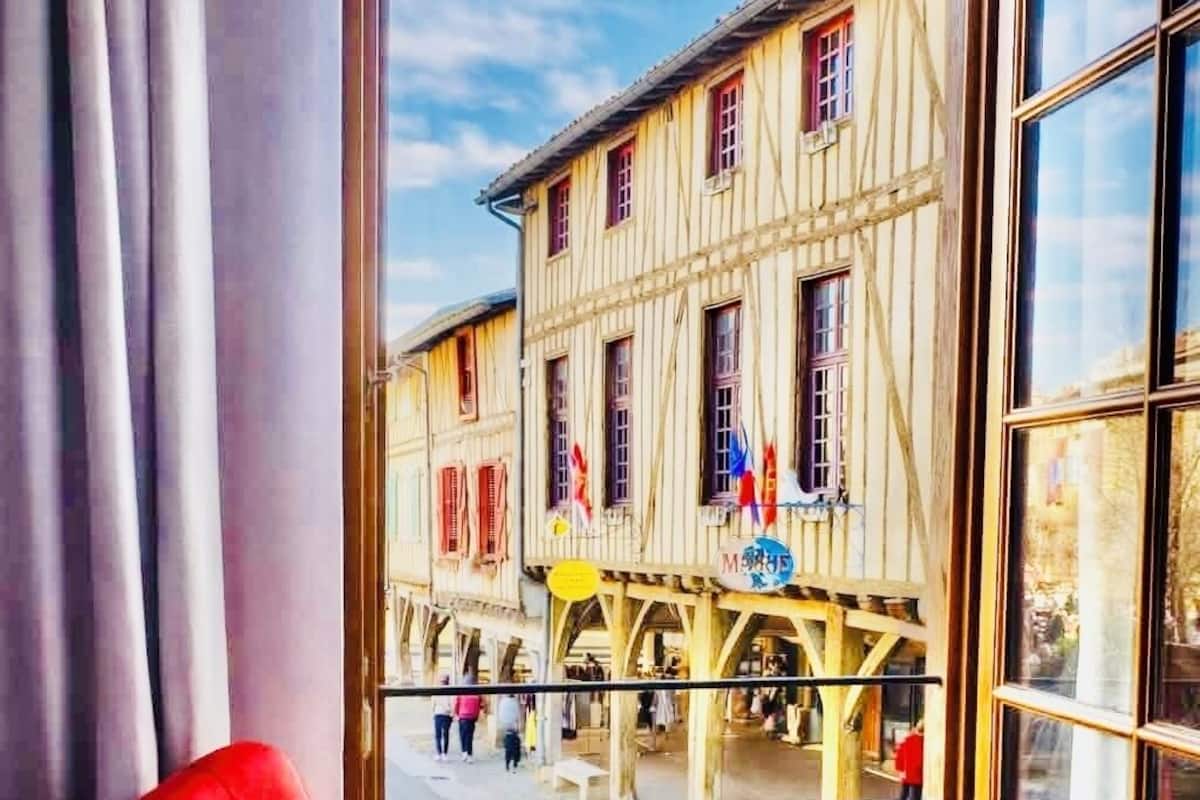 A room with a large window overlooking a historic building with multiple windows and flags.