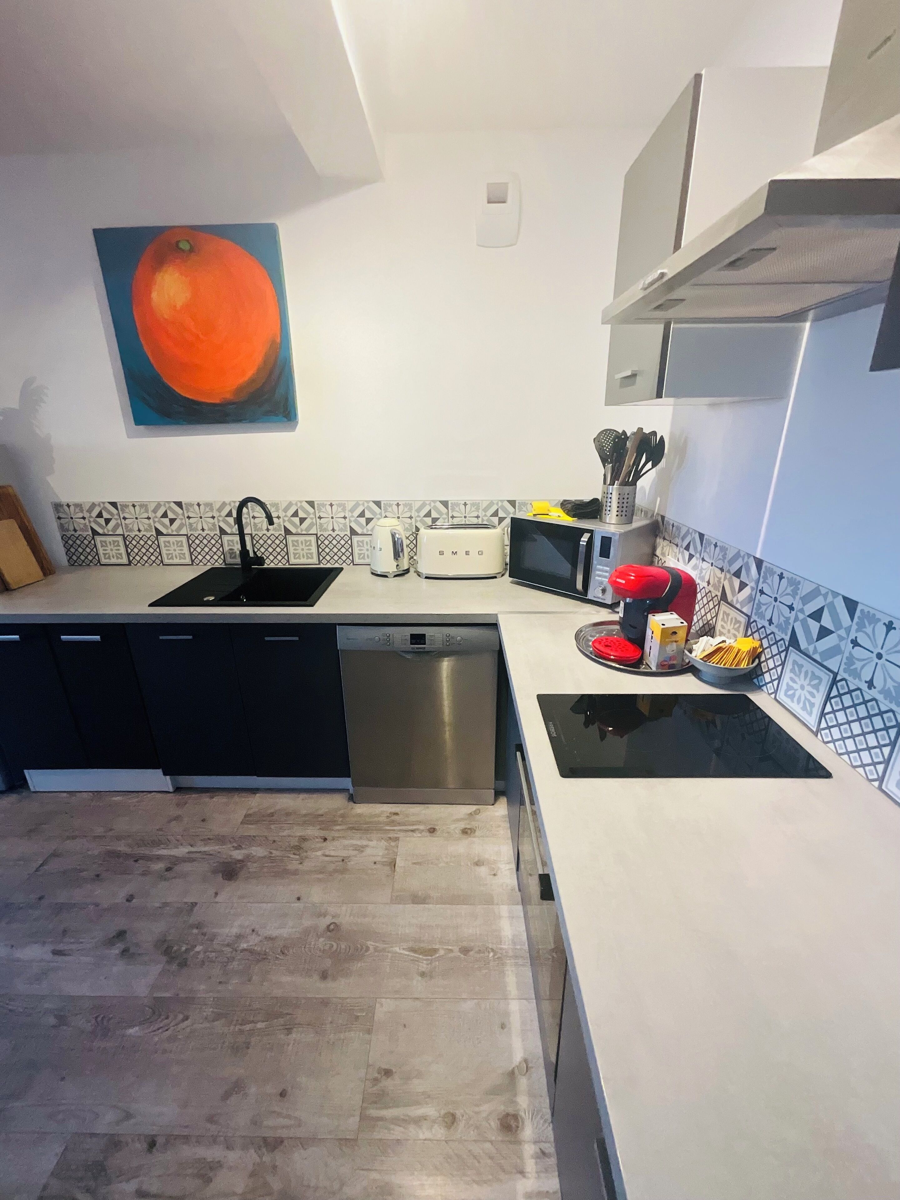 A modern kitchen with a dishwasher, microwave, toaster, and a sink.