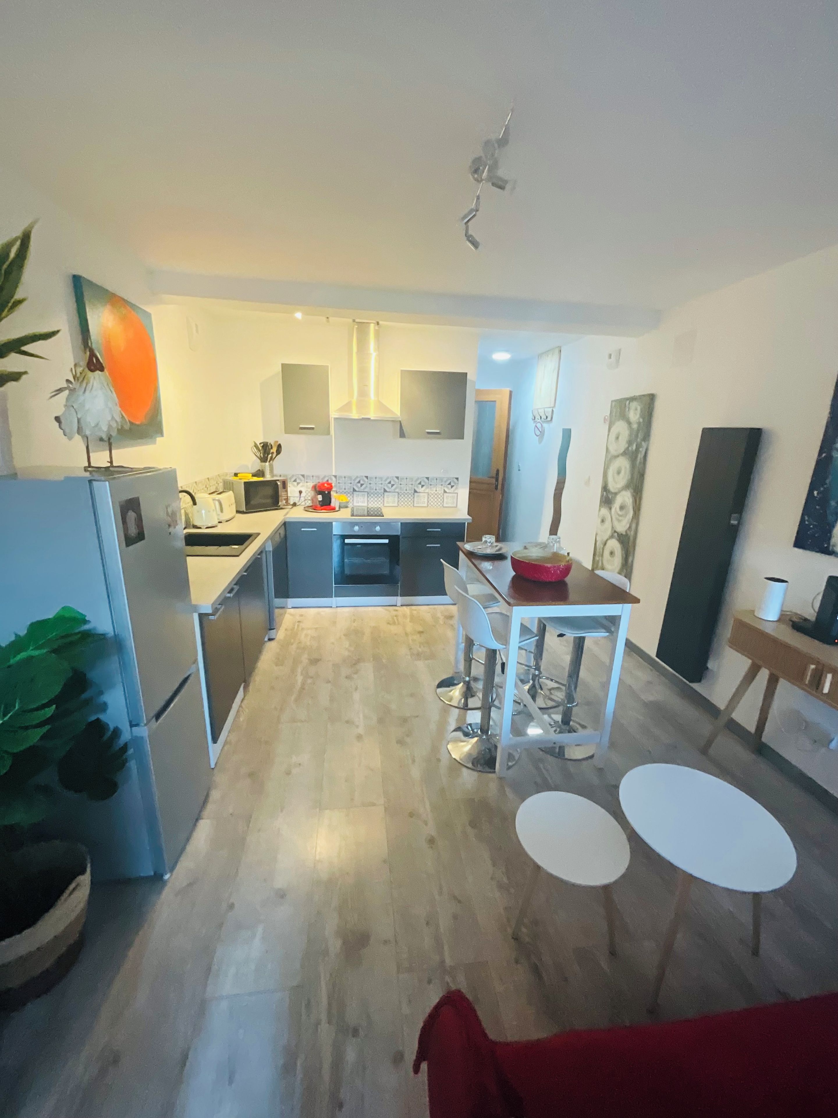 A modern kitchen with a central island, white cabinets, and a wooden floor.