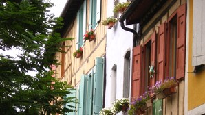 A row of traditional European buildings with balconies adorned with flower boxes. - Labyrinthe (Mirepoix)