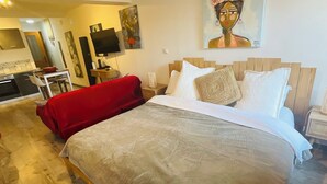 A hotel room with a bed, a red chair, a TV, and artwork on the walls. - Labyrinthe (Mirepoix)