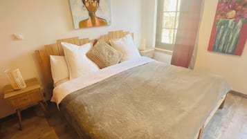 Une chambre avec un grand lit, une tête de lit en bois et un tableau au mur.