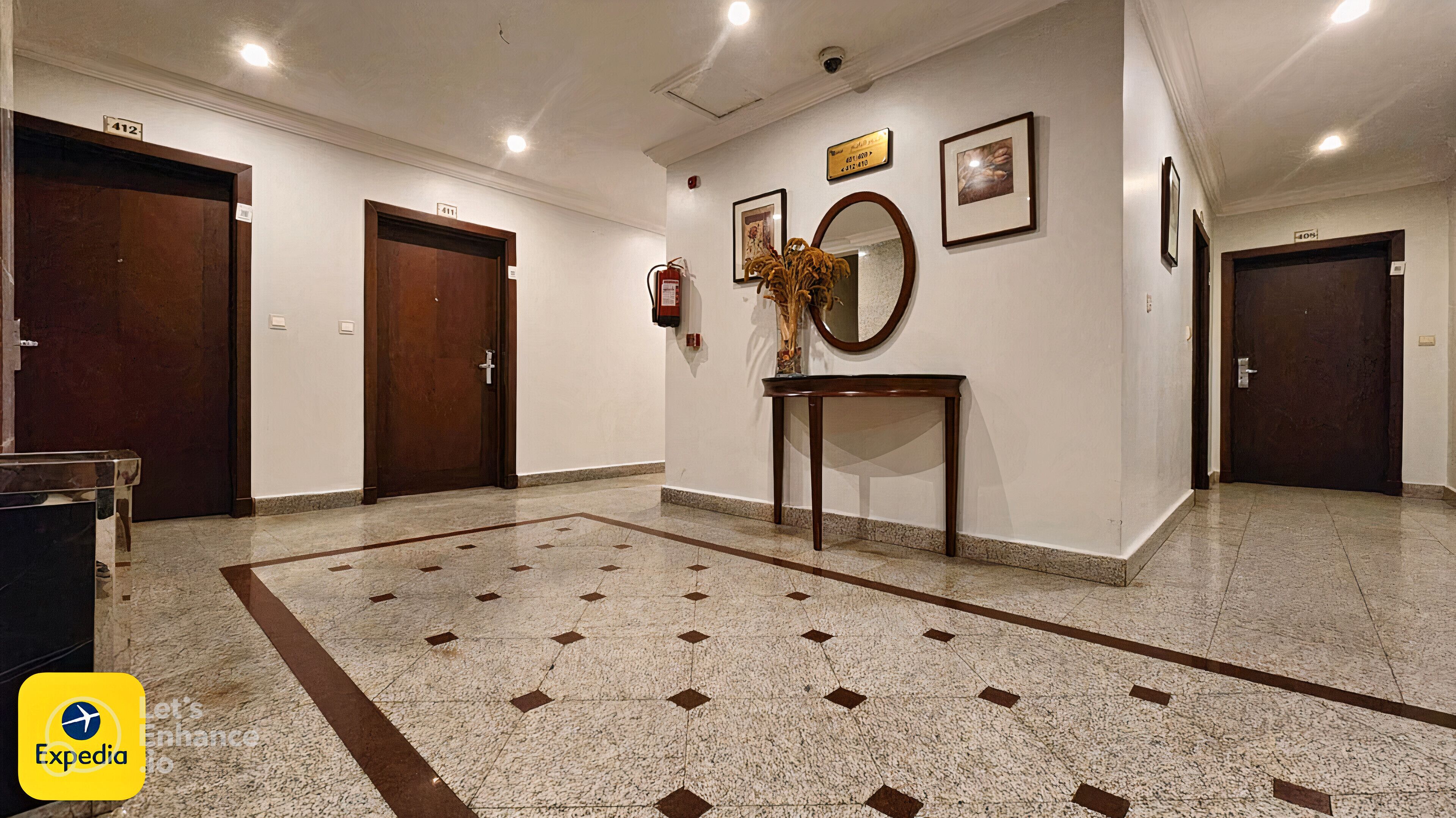 A hotel lobby with a marble floor, wooden doors, a reception desk, and framed artwork on the walls.