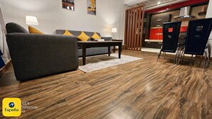 Un salon moderne avec un canapé gris, un plancher en bois et un coin repas doté de chaises noires.