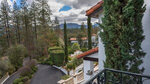 Un paysage montagneux avec une route sinueuse, un bâtiment blanc doté d’un toit rouge et un balcon avec une balustrade.