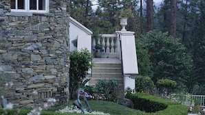 Une maison en pierre à l’extérieur blanc, dotée d’un balcon et d’un jardin bien entretenu.