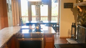 A kitchen with a built-in oven, a dining area with a table and chairs, and a stone fireplace. - Cozy Mountain Log Cabin With Amazing Views!  (Pine)