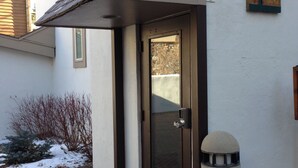 A modern building entrance with a glass door, a metal bollard, and a brick pathway. - Perfect Location - Steps to Gondola Walking/Bike Path Close to Restaurants Shops (Vail)