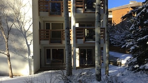 A multi-story building with large windows and balconies, surrounded by snow-covered ground and trees. - Perfect Location - Steps to Gondola Walking/Bike Path Close to Restaurants Shops (Vail)