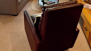 A modern living room with a sofa, armchair, and glass coffee table. There is a fireplace and a bookshelf with books. - Perfect Location - Steps to Gondola Walking/Bike Path Close to Restaurants Shops (Vail)