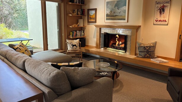 A cozy living room with a fireplace, a sofa, a coffee table, and a bookshelf. - Perfect Location - Steps to Gondola Walking/Bike Path Close to Restaurants Shops (Vail)