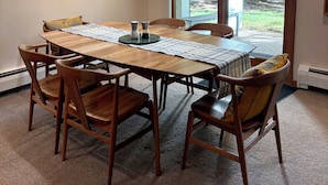 A dining area with a wooden table and chairs, a painting on the wall, and a view of greenery outside. - Perfect Location - Steps to Gondola Walking/Bike Path Close to Restaurants Shops (Vail)