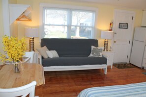 A cozy room with a wooden dining table, a sofa, and a small kitchen area.