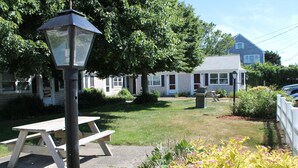 Ein Picknicktisch und eine Straßenlaterne in einem Gartenbereich, im Hintergrund ein Haus.