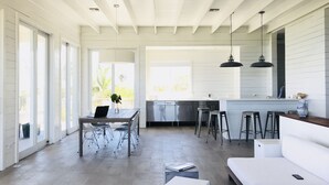 Amplia sala de estar con un sofá grande, una mesa de comedor con sillas y una zona de cocina con taburetes de bar.