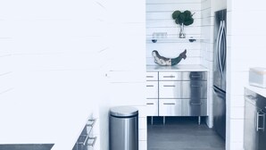 Una cocina moderna con armarios blancos, electrodomésticos de acero inoxidable y piso de baldosas grises.