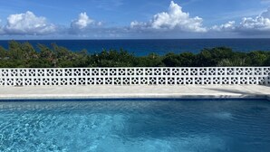 Una piscina con vista al océano y una cerca blanca.