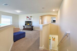 Ein Wohnzimmer mit einem blauen Sofa, einem Flachbildfernseher und einem Gemälde an der Wand.