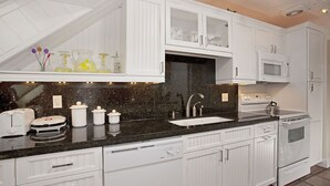 Una cocina moderna con armarios blancos, encimera negra, horno empotrado y microondas.