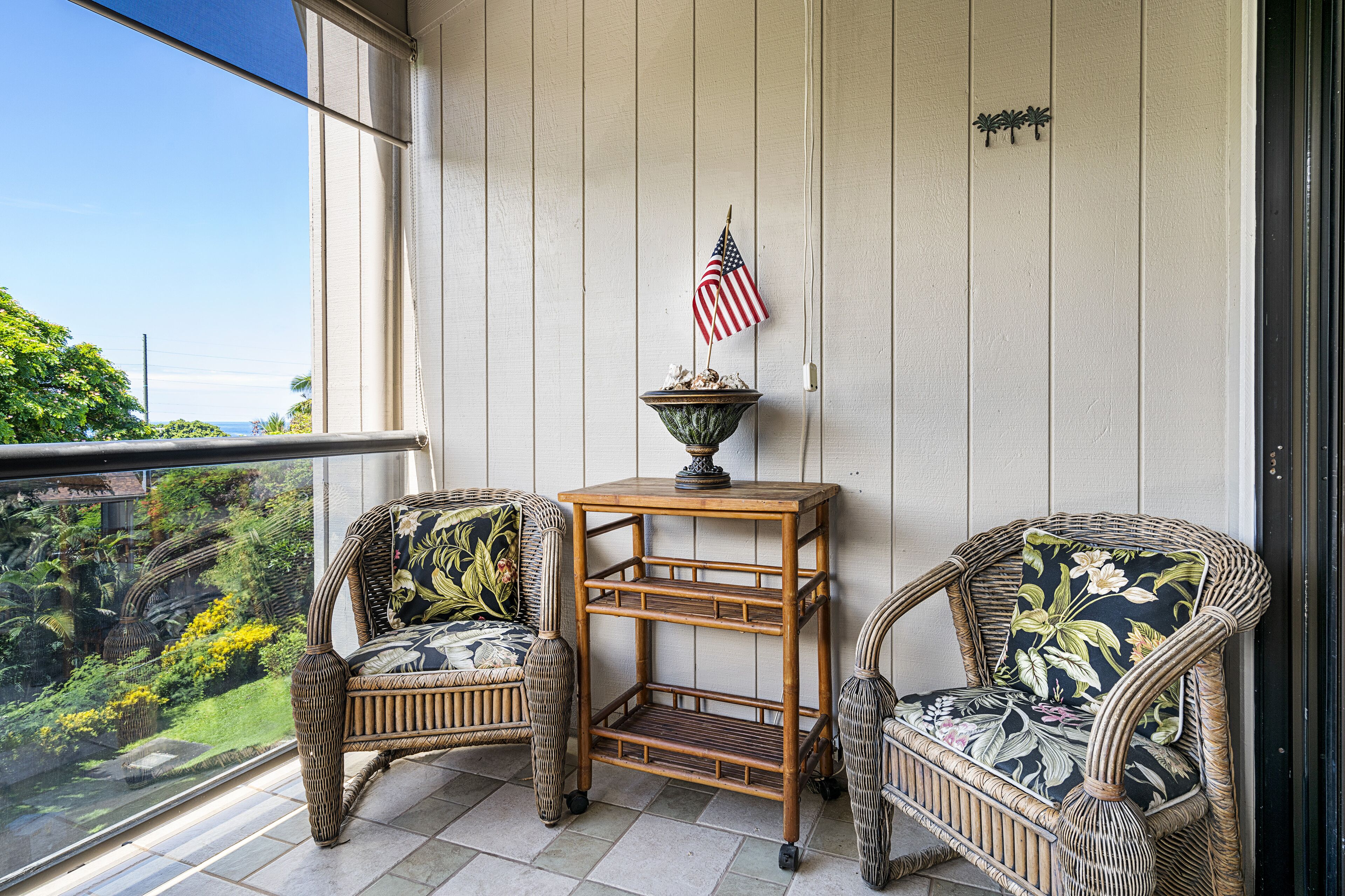 Een balkon met rieten stoelen, een kleine tafel, en een Amerikaanse vlag.