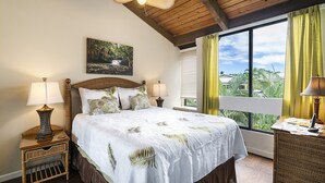 Una camera da letto con un letto grande, due comodini con lampade, una finestra con tende e un quadro appeso al muro.
