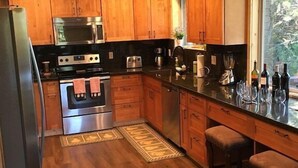 Una cocina moderna con armarios de madera, electrodomésticos de acero inoxidable y una barra con taburetes.